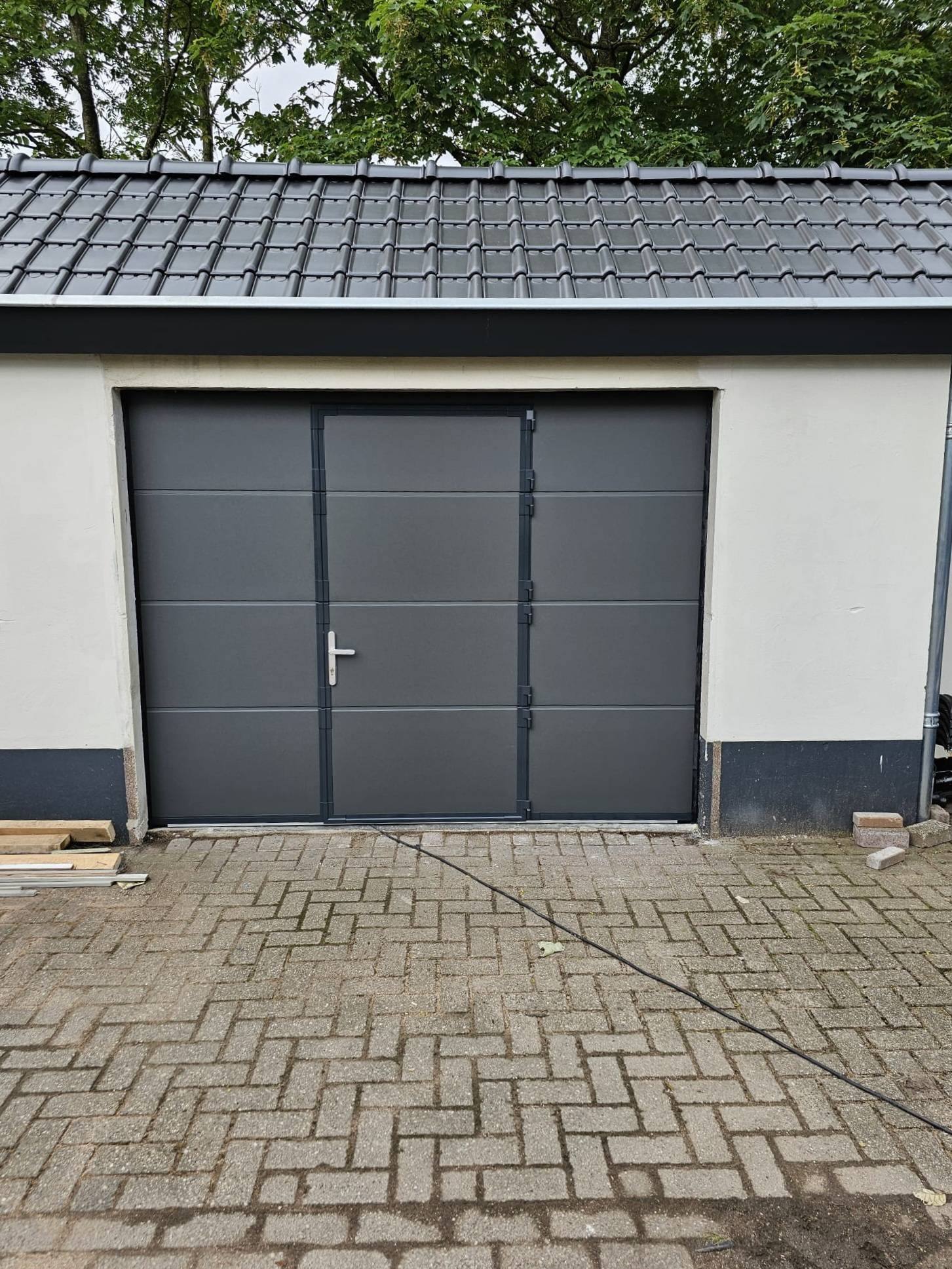 Antracietkleurige garagedeur met deurblad en deurkruk in een witte garage