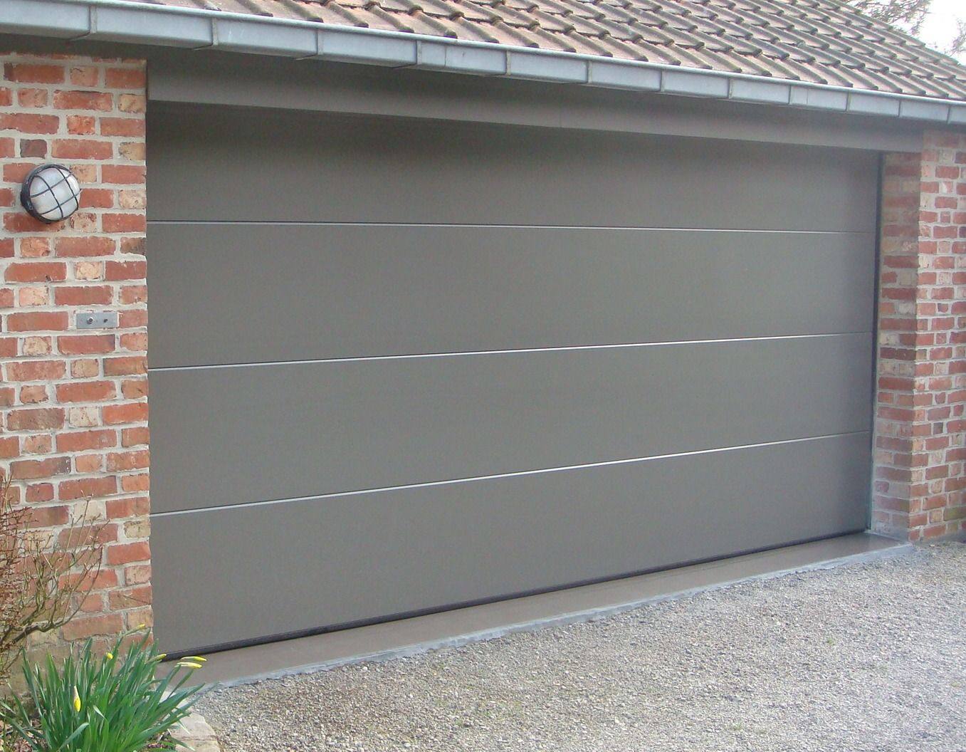 Grijze sectionaal garagedeur met strakke panelen in een bakstenen gevel