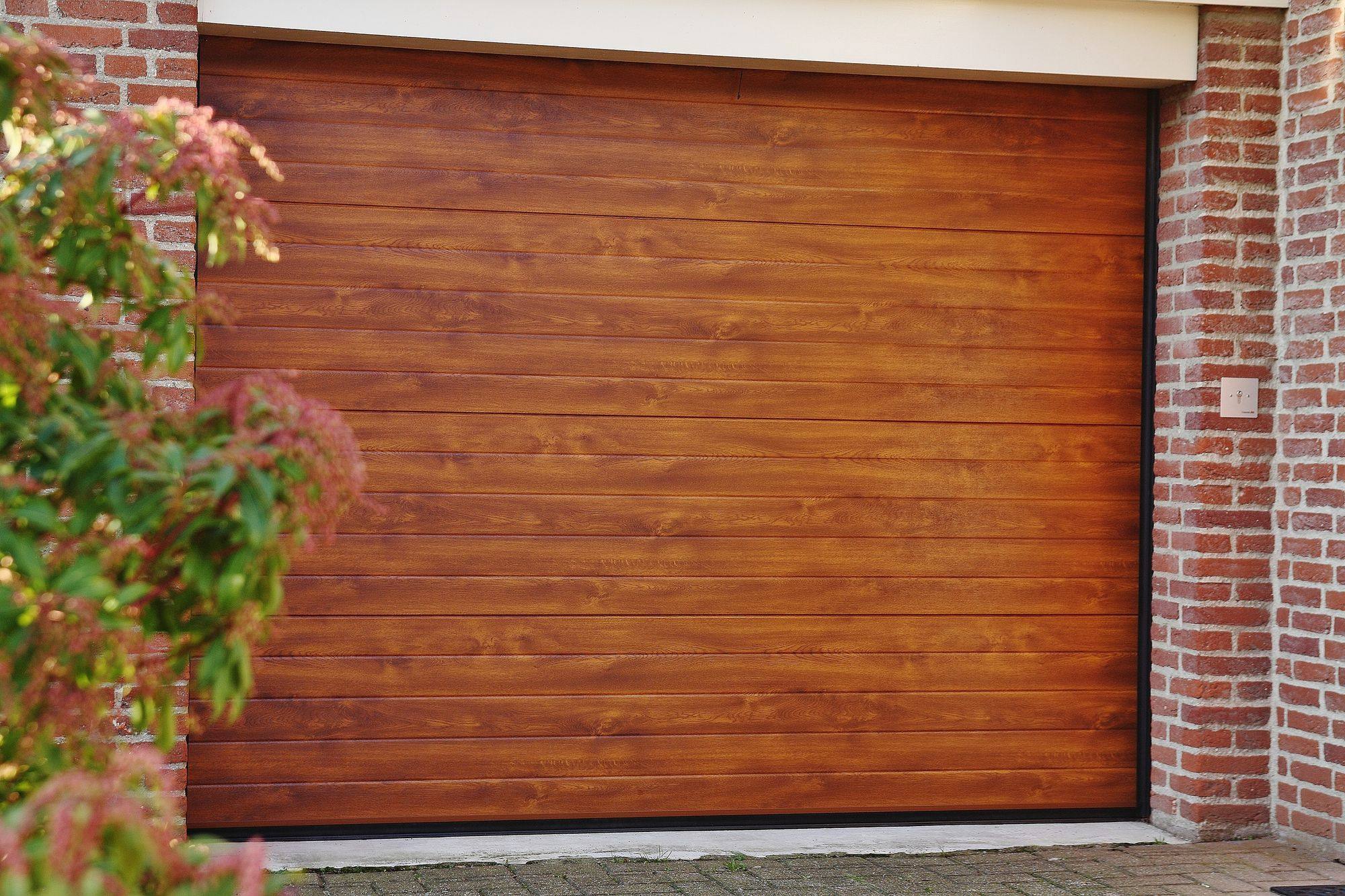 Sectionaal garagedeur in houtlook in een rode bakstenen gevel