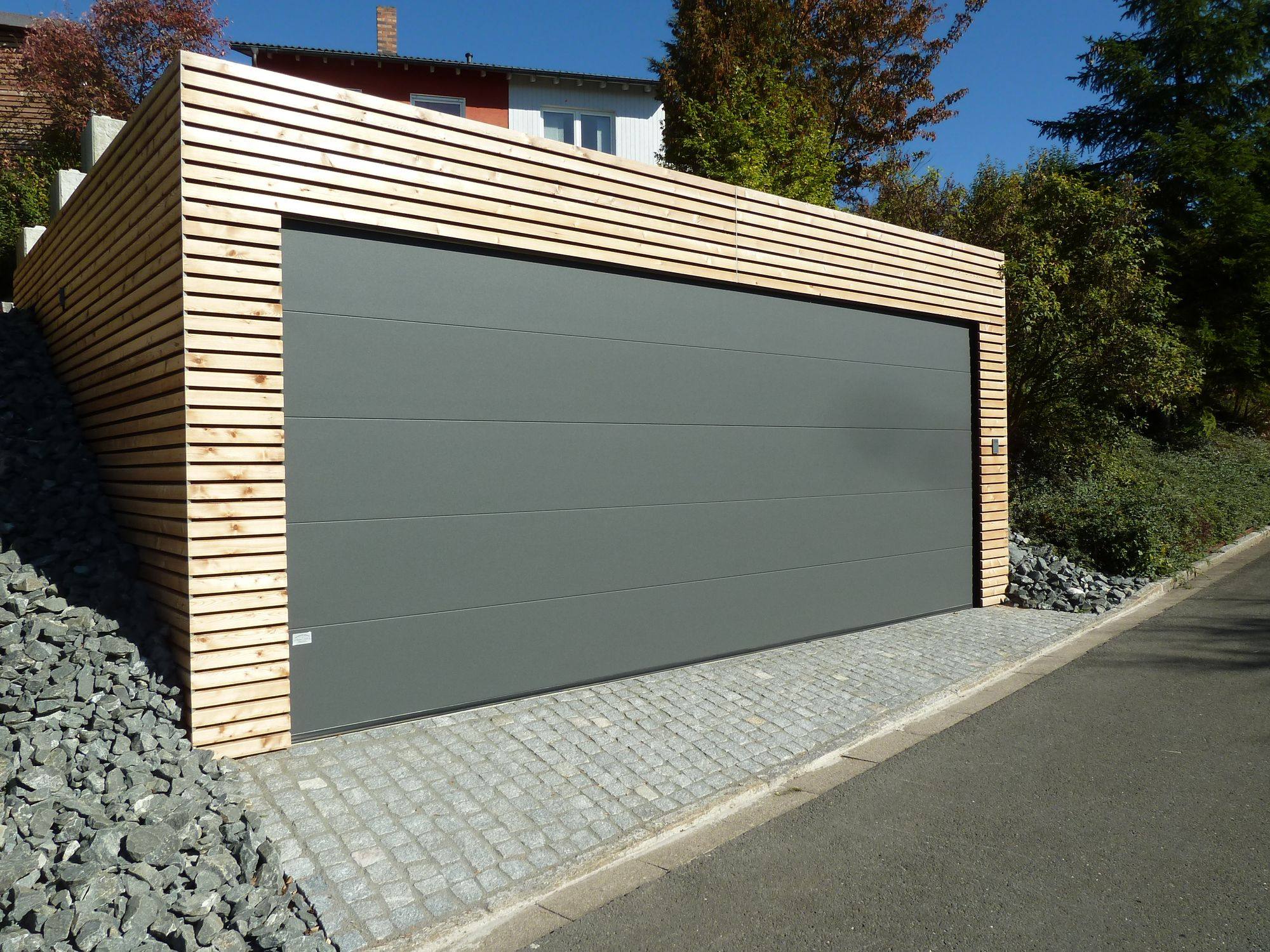 Grijze sectionaal garagedeur in een vrijstaande garage met houten latten