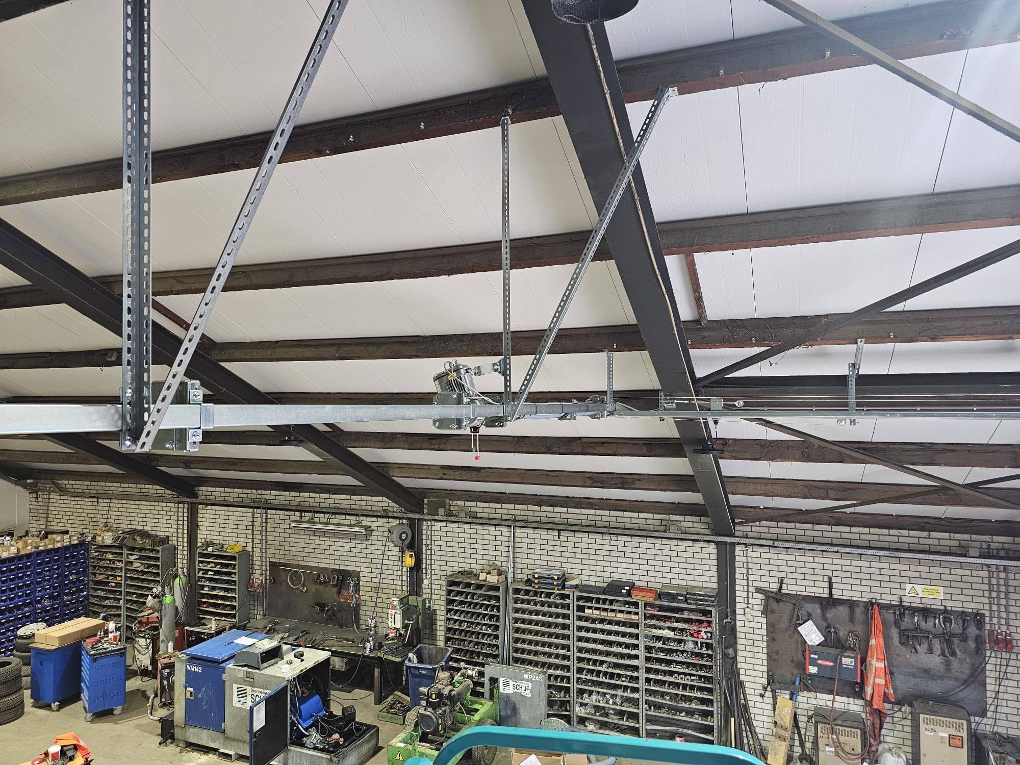 Aandrijving en ophangconstructie van een industriedeur onder het plafond van een werkplaats