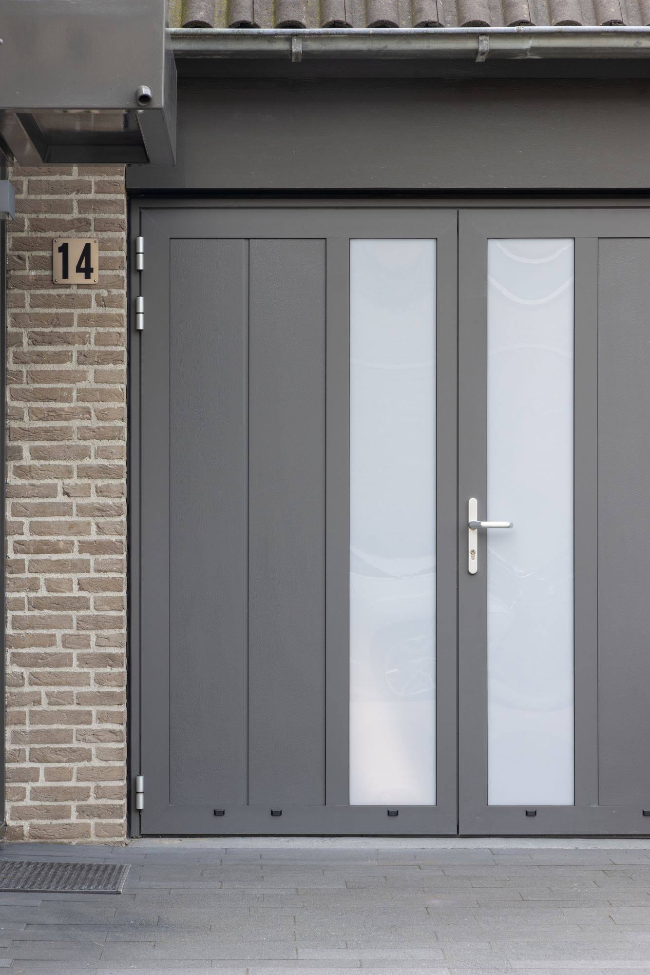 Grijze openslaande garagedeur met matglazen stroken bij een woning