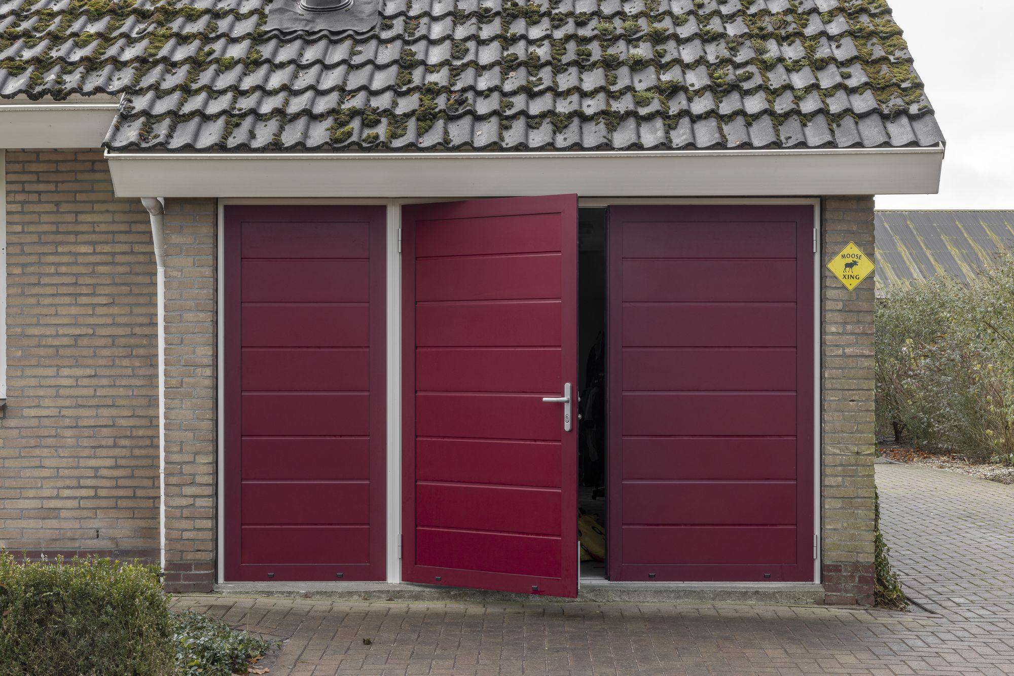Rode openslaande garagedeur met één deurvleugel open