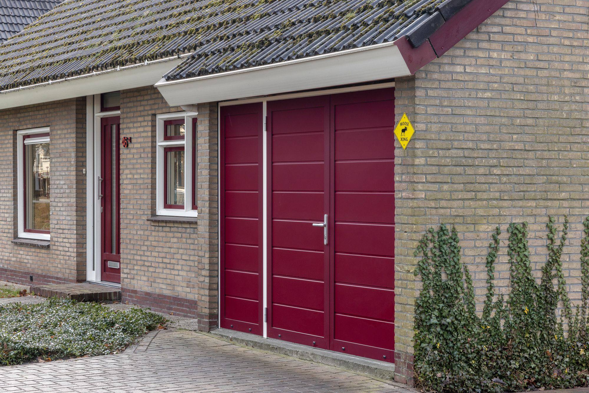Rode openslaande garagedeur in de gevel van een woning